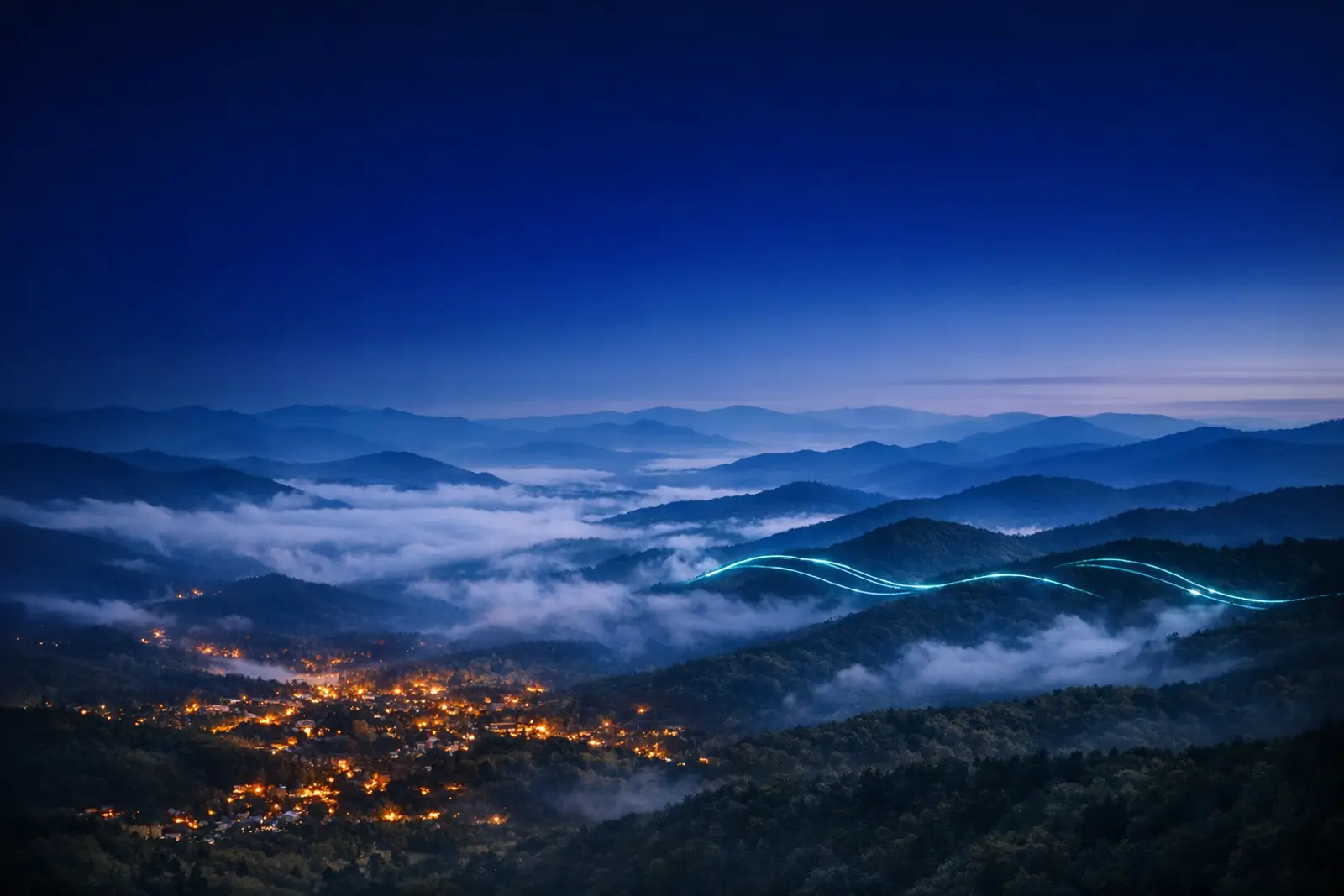 The Great Smoky Mountains at blue hour, fog in the valleys and town lights in the foothills